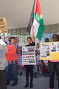 Woman holds a Palestinian flag and a sign protesting Israel