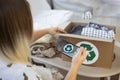 A woman holds a phone in her hands to take pictures of clothes folded in a box. A recycling sign is visible on the phone Royalty Free Stock Photo