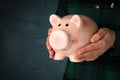 Woman holds Piggy bank on dark blue background Royalty Free Stock Photo