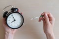 Woman holds a positive pregnancy test and alarm clock. Nine months of pregnancy. The concept of the biological clock of