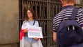 Woman holds a poster hands near administrative building Red white flag shoulders