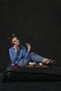 Woman holds retro phone and maffins. Girl with bright makeup smiling and bun hairstyle in studio on black background