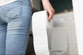 Woman holds roll of toilet paper in her hand while going to toilet