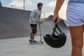 A woman holds a safety helmet after riding in an extreme park. The skate park, rollerdrome, quarter and half pipe ramps. Extreme