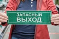 Woman holds a sign with a Russian Cyrillic inscription emergency exit. Close up Royalty Free Stock Photo