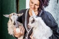 A woman holds small little goats on her hands. Love for pets. Th