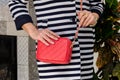 Woman holds a small stylish bag clutch of bright red color wit