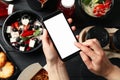 Woman holds smartphone Food in takeaway boxes on wooden background