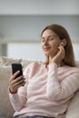 Woman holds smartphone listens music through modern wireless earphones Royalty Free Stock Photo