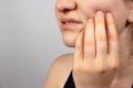 A woman holds a sore tooth with her hand. Dental pain in dentistry, pulpitis and tooth decay, nerve removal. Stomatitis