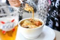 A woman holds a spoon over a delicious bowl of French onion soup at an outdoor cafe in Paris France