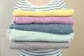 Woman holds a stack of clean terry towels. Folding clean linen