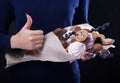 Woman holds a sweet eatable bouquet wrapped in paper on black background Royalty Free Stock Photo