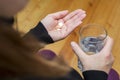 Woman holds tablet and glass of water. Female going to take tablet from headache or painkiller or abortion pill medication Royalty Free Stock Photo