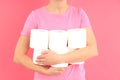 Woman holds toilet paper on pink background. Hemorrhoids concept