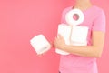 Woman holds toilet paper on pink background. Hemorrhoids concept