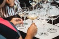 Woman holds two glasses of white wine. people consider the color of the wine and try how it smells in different glasses