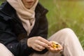 A woman holds various dried fruits and nuts in her hand. Sits on the green grass in the forest. Snack during the hike, walk. Royalty Free Stock Photo