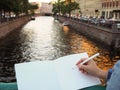 Woman holds a white journal while standing on the bridge on the city river background. Royalty Free Stock Photo