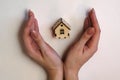 Woman holds wooden model house in hands on a light background Royalty Free Stock Photo