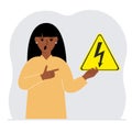 A woman holds a yellow triangular warning sign with a black lightning in his hand. The concept of the danger of electric