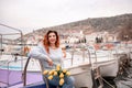 Woman holds yellow tulips in harbor with boats docked in the background., overcast day, yellow sweater, mountains Royalty Free Stock Photo