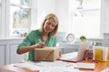 Woman At Home Addressing Package For Mailing