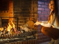 Woman at home fireplace making fire with bellows. Royalty Free Stock Photo