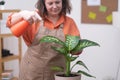 woman home garden caring for plants, watering repotting them into a decorative pot, fertilization