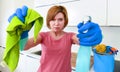 Woman at home kitchen in gloves holding cleaning scourer and detergent spray bottle rubbing with cloth Royalty Free Stock Photo