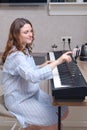 A woman in a home,kitchen learns piano from online lessons and sheet music on a mobile phone