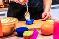 Woman at Home in the Kitchen puts the Dough in a colored Silicone Mold with a spoon