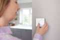 Woman At Home In Kitchen Turning Down Central Heating Thermostat To Save Energy And Money Royalty Free Stock Photo