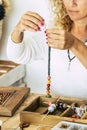 Woman at home make handmade jewellery. Box with beads on old wooden table. view with woman hands - tutorial to learn how to make Royalty Free Stock Photo