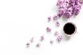 Woman home office with lilic flowers and cup of coffee white desk background top view mock up