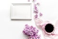 woman home office with lilic flowers frame and cup of coffee white desk background top view mock up