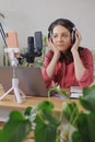 woman in a home office records podcast audio content with a microphone and headphones and a labrador dog