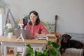 woman in a home office records podcast audio content with a microphone and headphones and a labrador dog