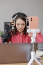 woman in a home office records podcast audio content with a microphone and headphones and a labrador dog