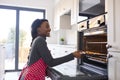 Woman At Home Putting Baking Tray Of Cookies In Oven Royalty Free Stock Photo