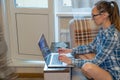 A woman at home quarantines a couch with a laptop. Work from home