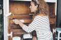 Woman at home restore old wooden cabinet painting with a roller and white pain. New refurbish and recycling leisure activity Royalty Free Stock Photo