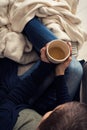 Woman at home sitting in comfy armchair and drinking tea