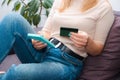 A woman at home sitting on a sofa holds a credit card in her hands and makes a payment using a laptop. happy online shopper