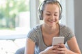 Woman At Home Streams Music From Mobile Phone To Wireless Headphones Royalty Free Stock Photo