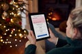 Woman At Home Using Digital Tablet To Apply For Credit Card Online At Christmas