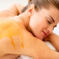 Young woman with honey on back laying on massage table Royalty Free Stock Photo