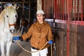 Woman horse holder leading white horse in stabling Royalty Free Stock Photo