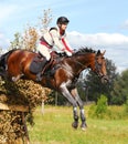 Woman horseback jumping Cross-Country