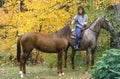 Woman on horseback leading horse, New England in Autumn